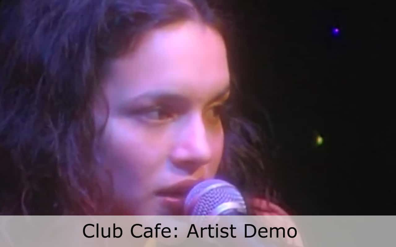 Live at Club Cafe Artist Demo features a close up of artist Nora Jones singing into the microphone on the Club Cafe stage, words below her read; Club Cafe: Artist Demo (video production by Merging Media).