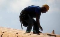 A man in a blue shirt and yellow hard hat, wears a tool belt while helping the 84 Lumber Joplin tornado rebuild in Missouri (video produced by Merging Media).
