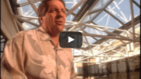 USWeb National Airlines Case Study video thumbnail is a man wearing a white button up answering interview questions about National Airlines against a back drop if an airport lobby, large white round beams crossing in front of a ceiling of windows.