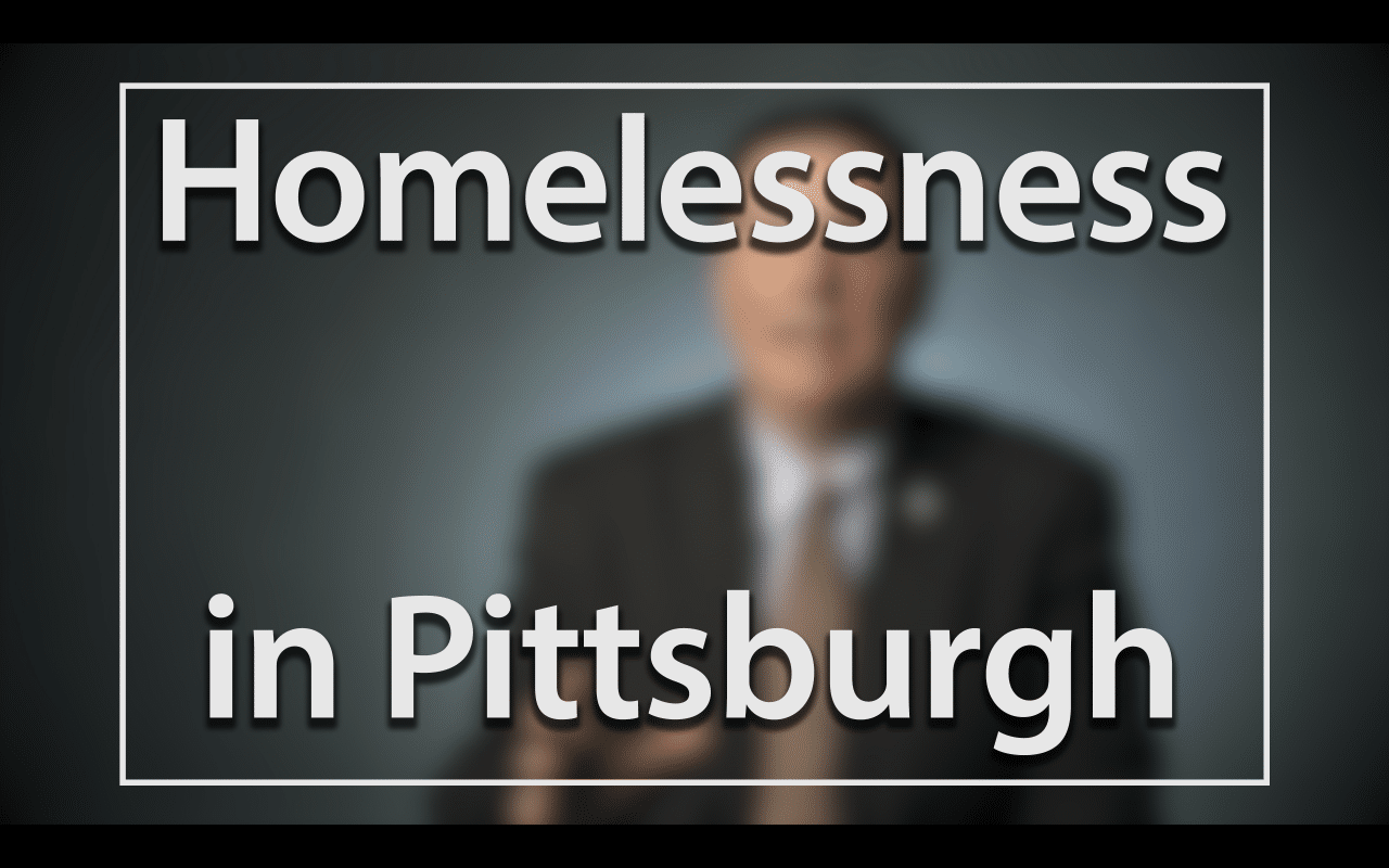 Mayor Peduto on Homelessness in Pittsburgh; Blurred figure of a man in a suit sitting in front of a very dark blue background, the large word in the foreground in white text reads; Homelessness in Pittsburgh (video produced by Merging Media).