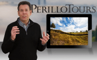 (Steve Perillo) Man wearing black half-zip sweater is standing next to a large image of an iPad with beautiful scene of a vacant Italian country side in this Perillo Tours Million Memories Commercial, text reads; Perillo Tours (video production by Merging Media)