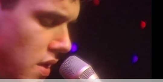 A close up of John Mayer singing into a microphone at Club Cafe (video produced by Merging Media)