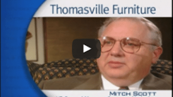 USWeb Solutions For The Information Age video thumbnail is an older gentleman with white hair and glasses with words below him labeling his name as Mitch Scott, sits for an interview, words above his head read; Thomasville Furniture.